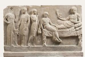 Commemorative relief. According to some scholars, it was dedicated to god Dionysus by a group of tragedy actors, after a performance. The actors are standing next to the god Dionysus, holding tambourines and masks. Dionysus is holding a horn, one of the most characteristic symbols of him. (ca. 400 B.C.), National Archaeological Museum of Athens.  